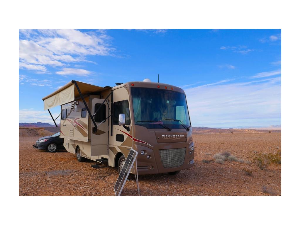 Winnebago Vista parked in desert landscape with portable solar panels in use