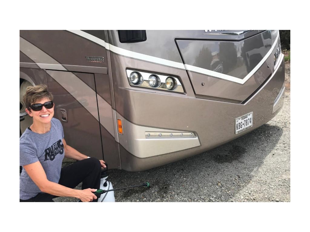 Woman sprays bug spray around campsite and motorhome to repel bugs