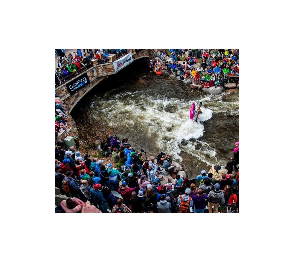Crowd of people gathered watching kayaker on a rapid.
