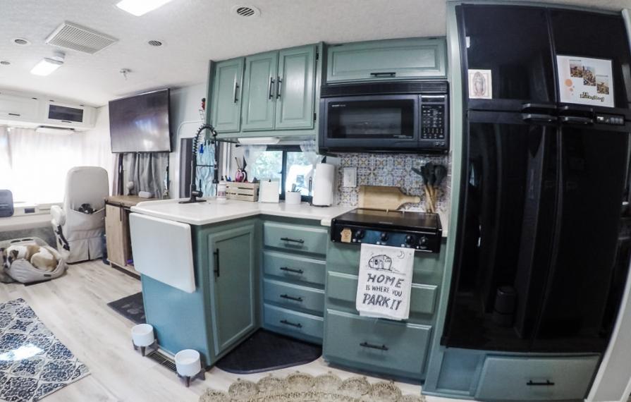 Finished kitchen with green cabinets and light flooring