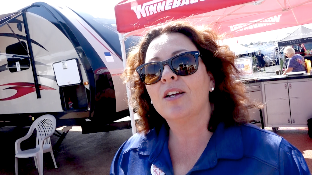 Jennifer Mink standing in front of Winnebago booth and display.