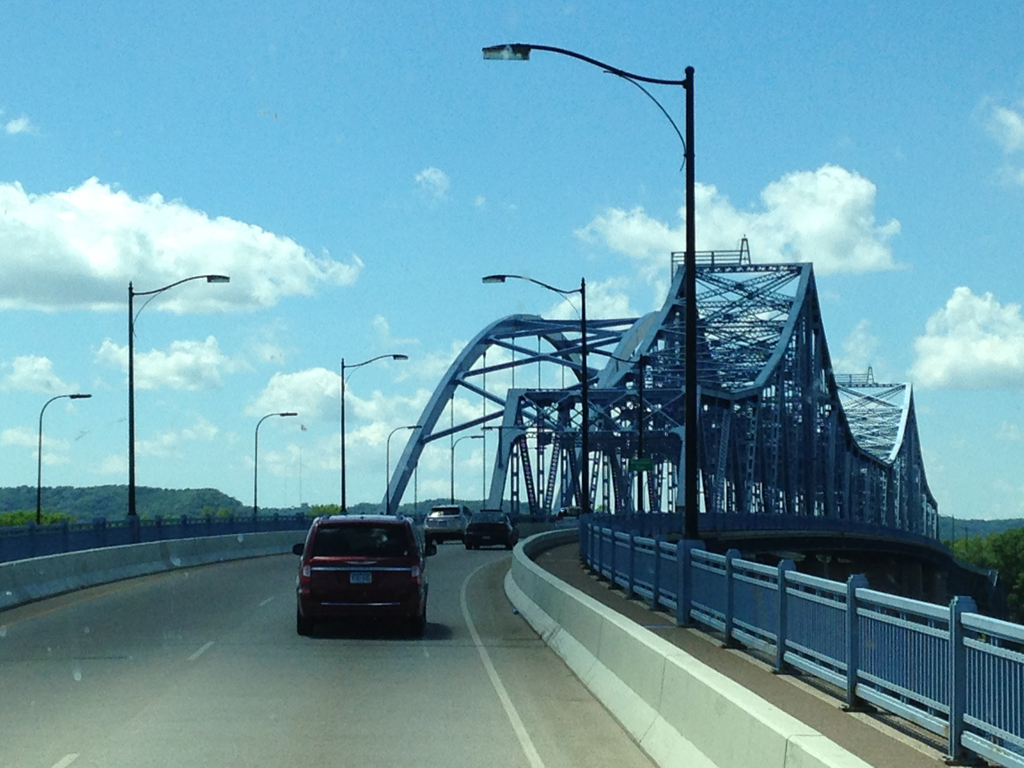 Cars crossing large blue bridge.