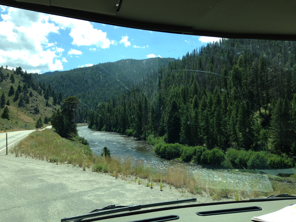 Road following a river at the base of the tree covered bluffs.