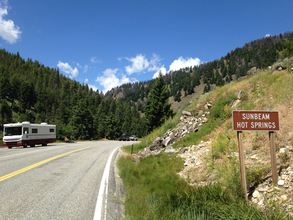 Winnebago Brave parked on the side of the road across from a sign for Sunbeam Hot Springs.