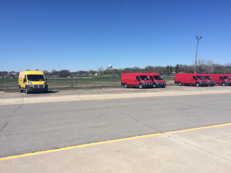 Yellow Winnebago Travato parked in lot among other red Travatos.