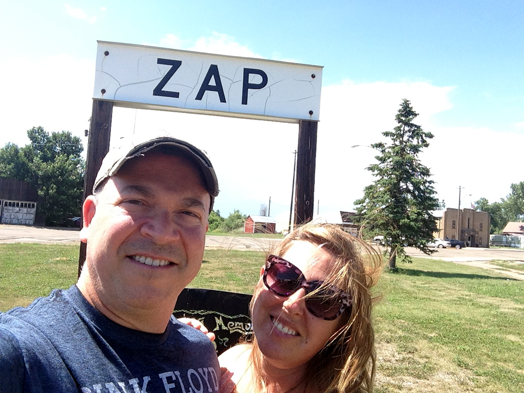 Couple taking a selfie in front of "ZAP" sign.