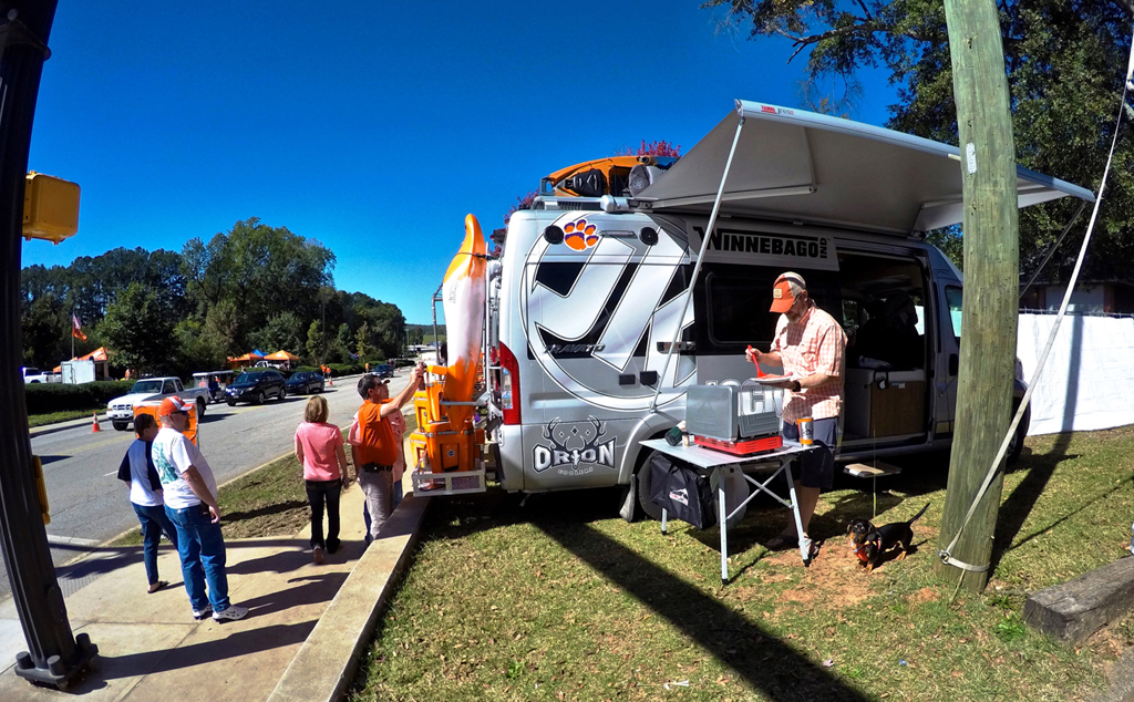 Person grilling under awning of Winnebago Travato.