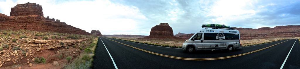 Winnebago Travato driving along highway with rocky canyons on both sides.