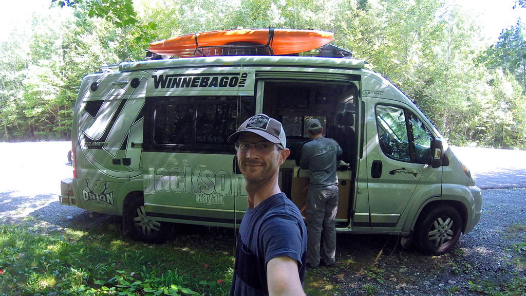 Man taking a selfie in front of a Winnebago Travato.
