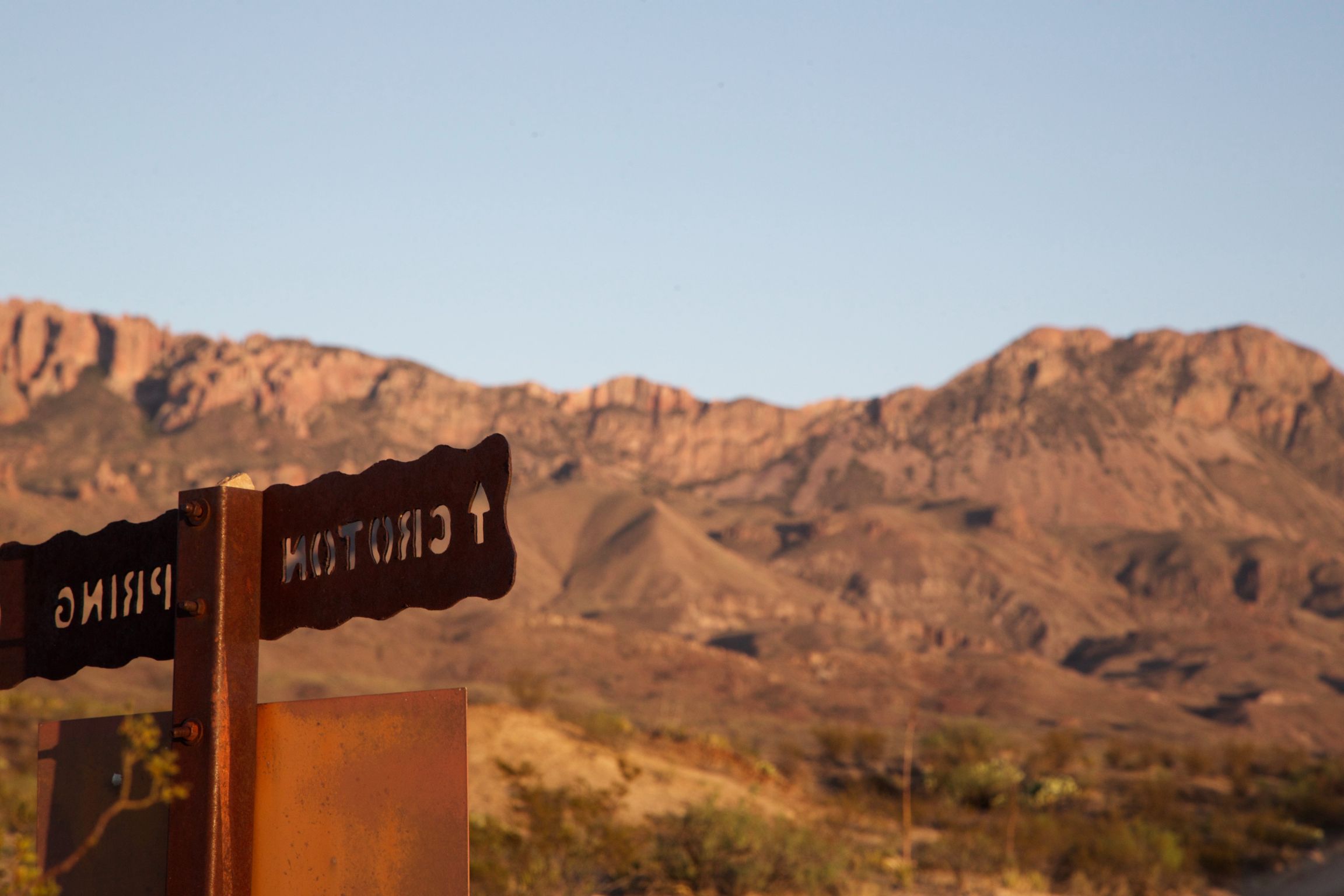 Sign pointing to Croton Springs with mountains in the background.