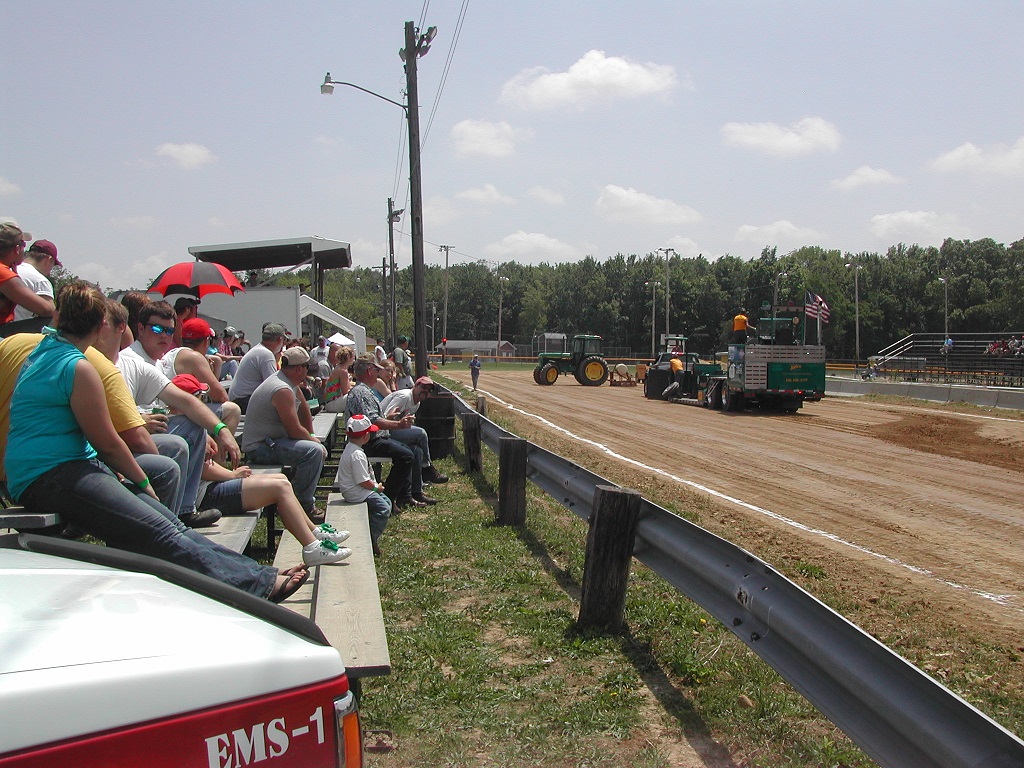 Crowd watching tractors on a dirt track.