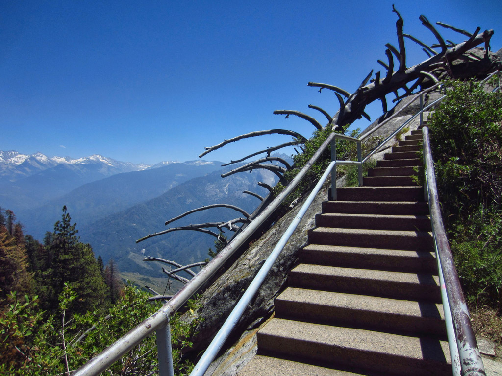 Steps leading up the side of the mountain with snow capped mountain range in the distance.