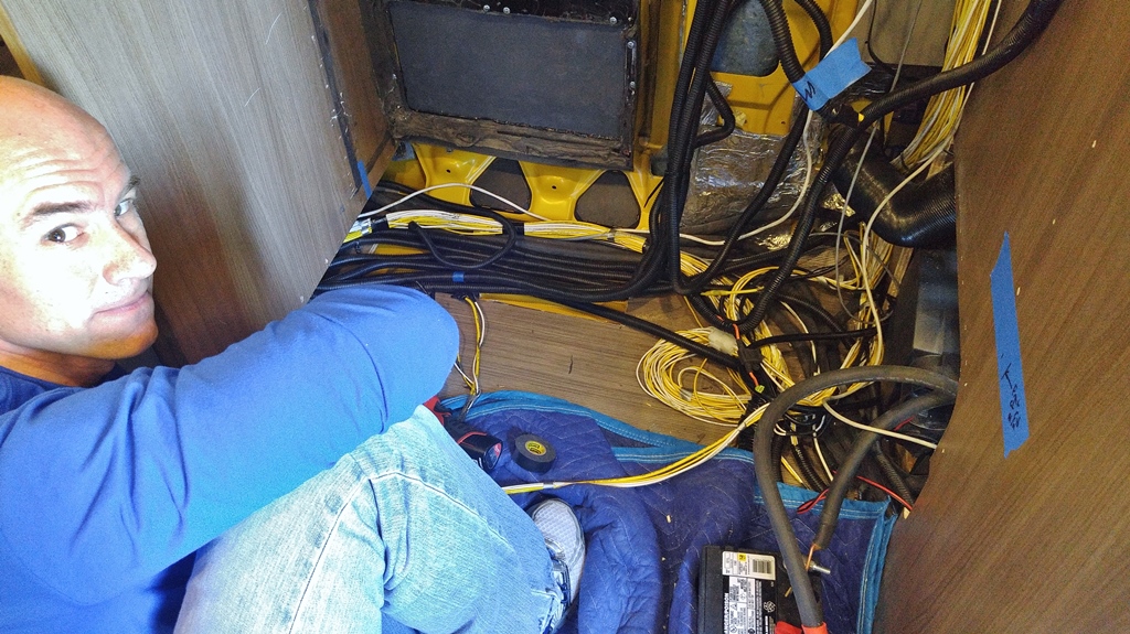 James on floor of Winnebago Travato with counter torn out and exposed wire and tubing showing.