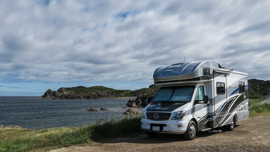 Winnebago View parked on the side of the road next to body of water.