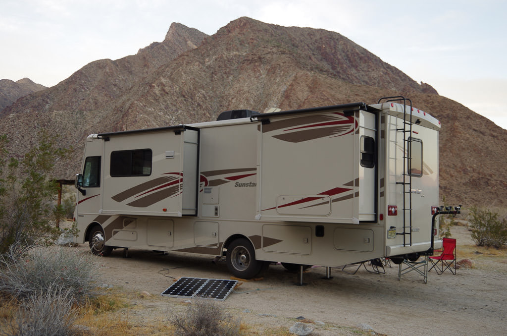 Winnebago Sunstar parked in campsite not far from the base of a mountain.