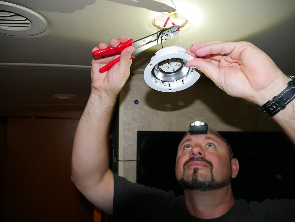A man replacing interior recessed light of his Winnebago Vista